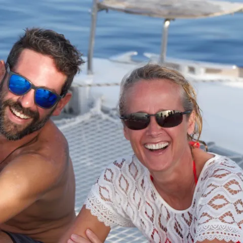 a man and a woman in sunglasses sitting in a boat on the water