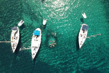 A drone photo of our sailboat in the bay of Kalogries in Milos, with guests swimming in crystal clear waters