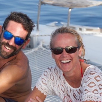 a man and a woman in sunglasses sitting in a boat on the water