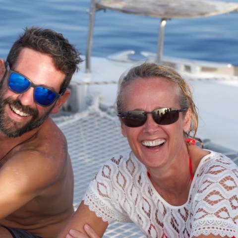 a man and a woman in sunglasses sitting in a boat on the water